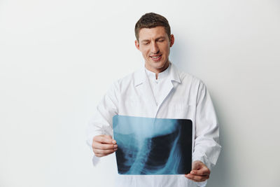 Portrait of doctor standing against white background