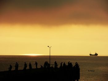 Silhouette people on beach against sky during sunset