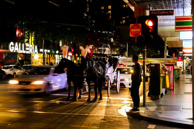 People walking on illuminated city street at night