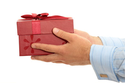 Close-up of hand holding red box against white background