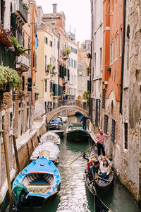 Boats moored in canal amidst buildings in city