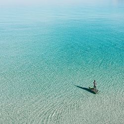 High angle view of mature man paddleboarding on sea during sunny day