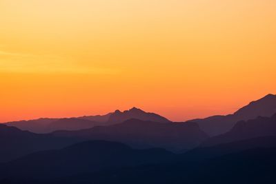 Scenic view of silhouette mountains against orange sky