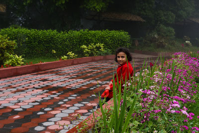 Portrait of young woman standing amidst plants