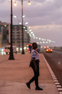 Rear view of woman standing on illuminated street