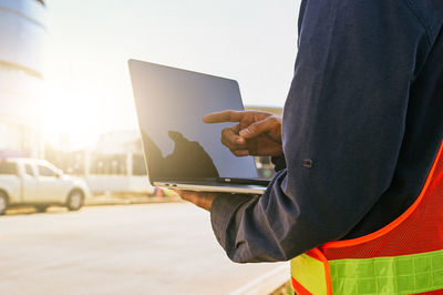 Midsection of man using digital tablet