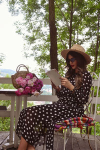 Young woman reading book while sitting at porch