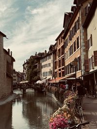 Canal amidst buildings in city against sky