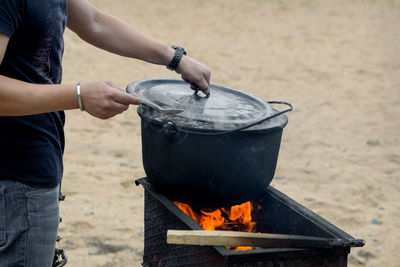 Midsection of man preparing food on barbecue grill