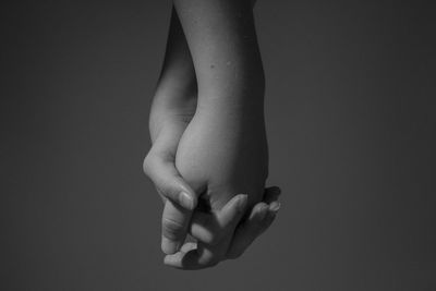 Cropped image of people holding hands against gray background