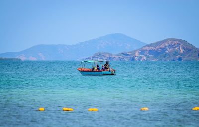 People in boat sailing on sea against clear sky