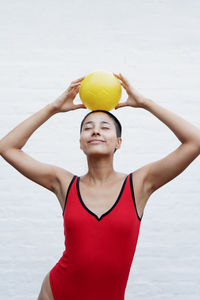 Portrait of young woman with arms raised standing against white background