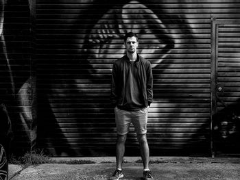 Full length portrait of young man standing against wall