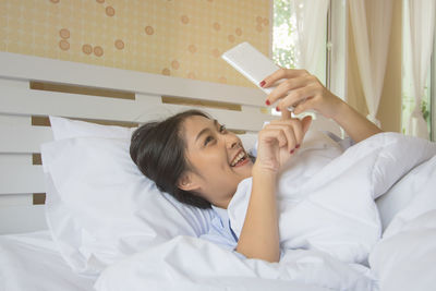 Young woman using mobile phone on bed