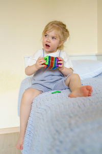 Cute little girl looking away while playing with magnetic construction toy in kids room