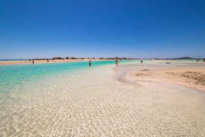 Scenic view of beach against clear blue sky