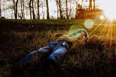 Man lying down on field against trees