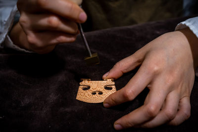 Chinese woman violin maker signs the jumper of her violin with fire with her name in the workshop