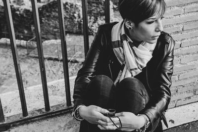 Full length of teenage boy sitting outdoors