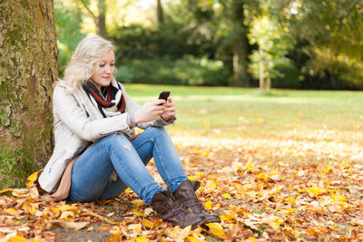 Young woman sitting on leaves in park