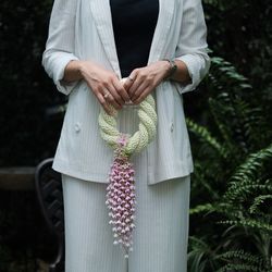 Midsection of woman holding wreath while standing by plants