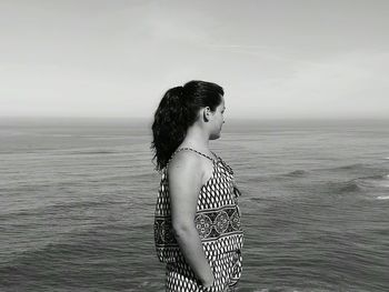 Rear view of young woman standing against sea