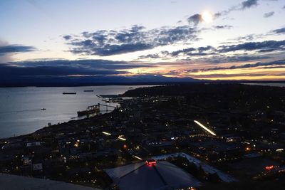 High angle view of illuminated buildings by sea against sky