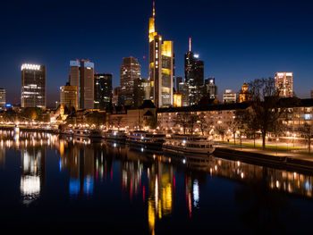 River by illuminated buildings against sky at night