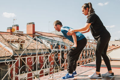 A couple doing training with rubber resistance band on their fooftop