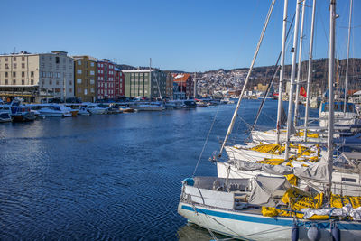 Boats moored at harbor by city against clear sky