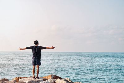 Rear view of man looking at sea against sky