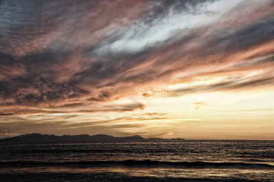 Scenic view of sea against dramatic sky during sunset