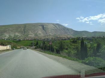 Road by mountains against sky