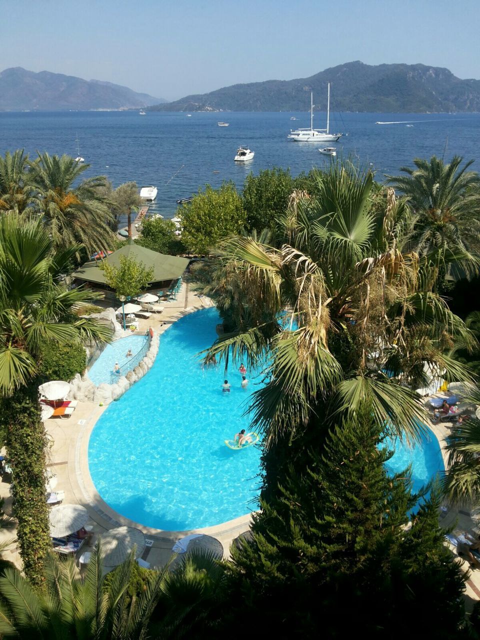 water, blue, mountain, tree, sea, tranquil scene, tranquility, scenics, beauty in nature, nature, palm tree, high angle view, nautical vessel, transportation, coastline, mountain range, lake, plant, clear sky, idyllic