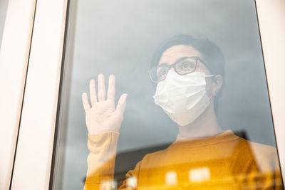 Woman wearing mask looking through window