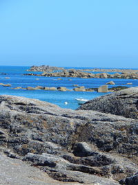 Rock by seascape against blue sky