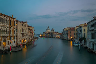 View of buildings at waterfront against cloudy sky