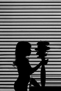 Side view of silhouette woman standing against wall