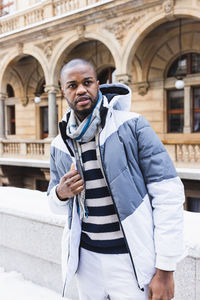 Young african man on street, snow winter season, city portrait