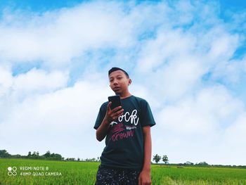 Full length of boy standing on field against sky