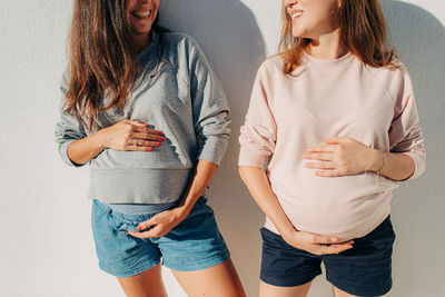 Midsection of friends standing against wall