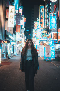 Portrait of woman standing on street in city at night