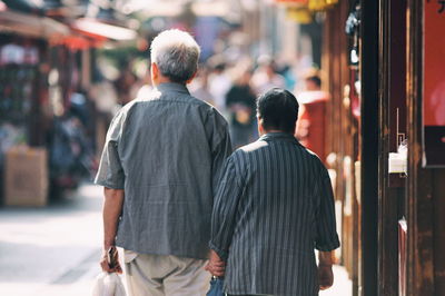 Rear view of people walking on street in city