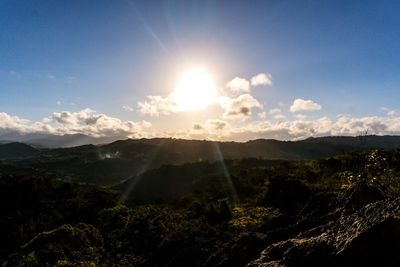 Sunlight streaming through mountains against sky