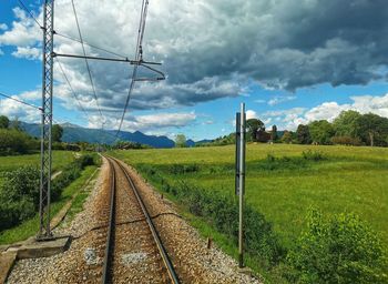 Railroad track amidst field against sky