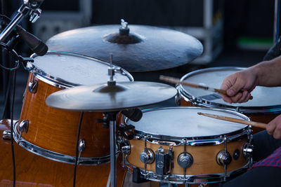 Cropped hands playing drum at night