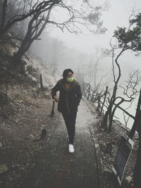 Full length of man wearing surgical mask while walking on footpath during winter