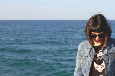 Beautiful young woman standing against sea