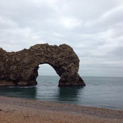 Rock formation at durdle door against cloudy sky