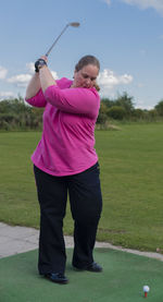 Full length of woman playing golf on field